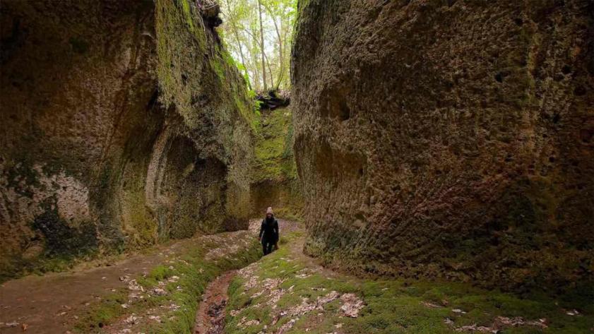 A walker on a sunken Etruscan path cut into tufa rock near Pitigliano