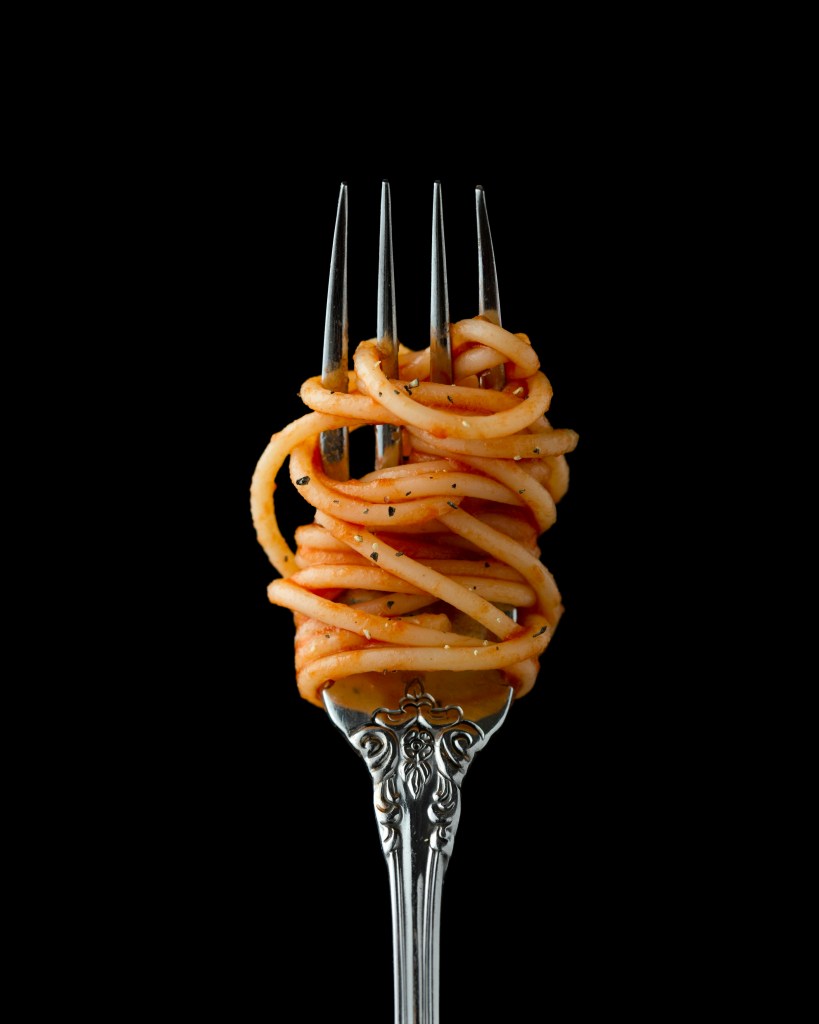 A fork twirled with spaghetti against a black background